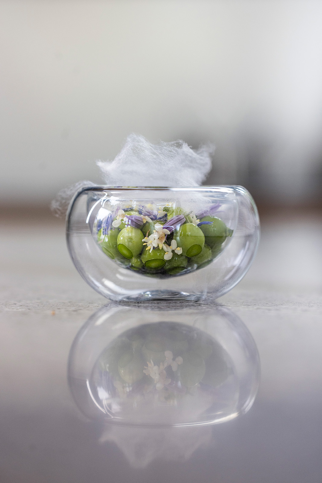en glasskål fyldt med blomster og røg